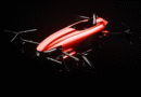 Red futuristic quadcopter drone with a glossy red fuselage and four rotor arms against a dark backdrop, looking ready to fly.